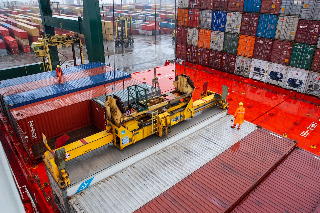 pexels-photo-28438290 Aerial view of workers managing cargo loading at a bustling port with vibrant shipping containers.