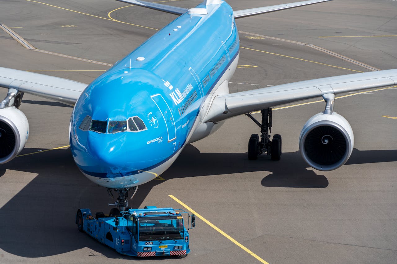 A large blue commercial aircraft being prepared for takeoff on a sunny day at the airport.